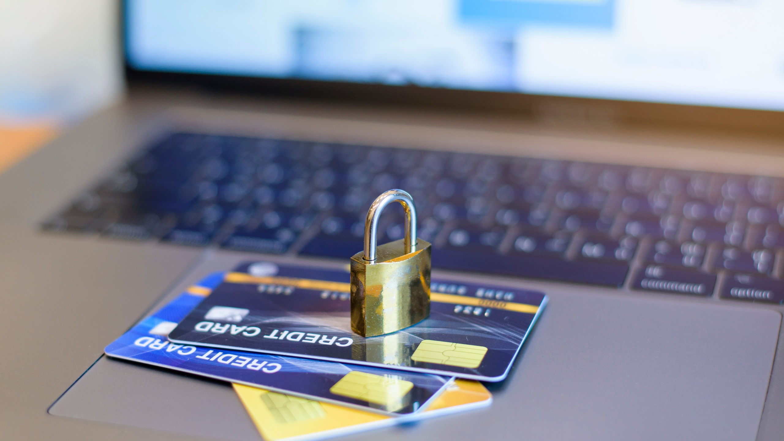 a padlock sits on top of credit cards next to a computer, demonstrating security from elder financial exploitation